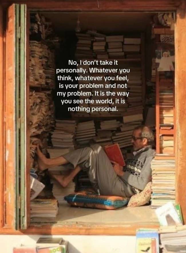 An older man reading in a cozy room filled with floor-to-ceiling books.