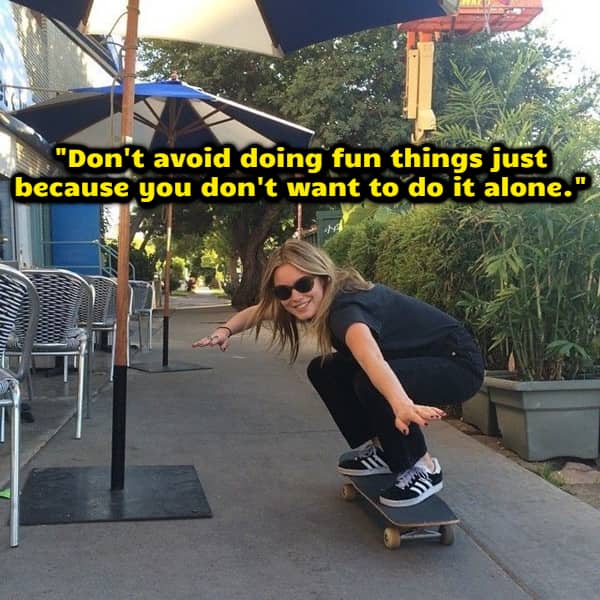 Woman riding a skateboard on a sidewalk with text encouraging people to do fun things alone.