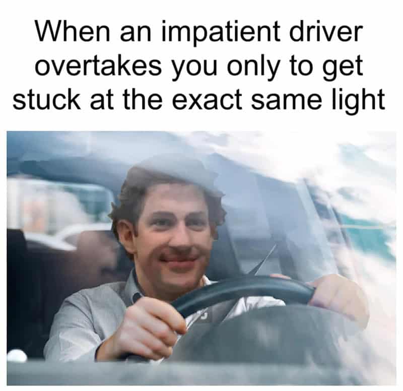 Jim Halpert smirks from behind a steering wheel in this relatable meme about driving frustration. It captures that peak moment of satisfaction when an aggressive driver speeds past you only to be stopped by the same red light directly in front of you