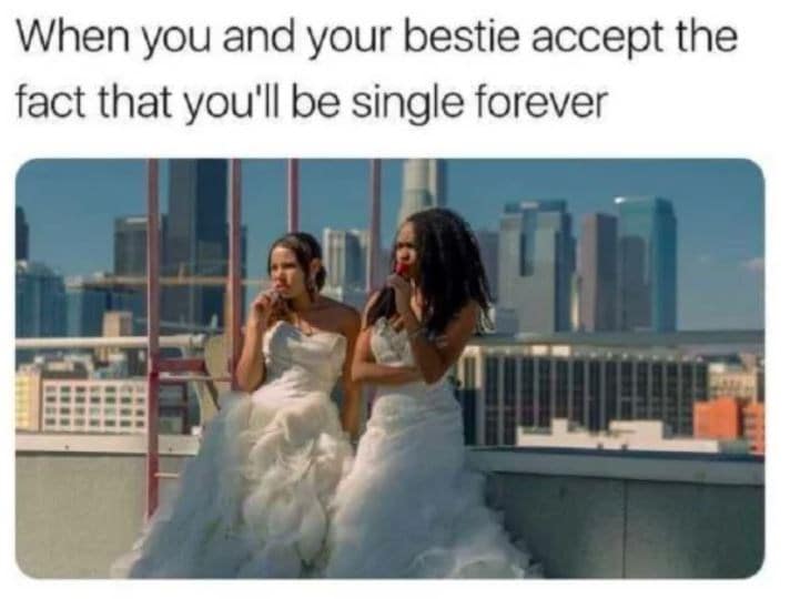 single meme of two best friends leaning against a rooftop railing in full wedding gowns, casually eating lollipops after accepting their "single forever" status.