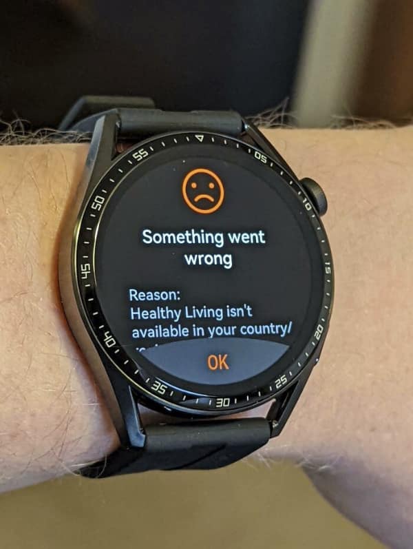 A smartwatch displaying a brutally honest system error—a tech fail with a frowny face emoji explaining that "Healthy Living isn't available in your country."
