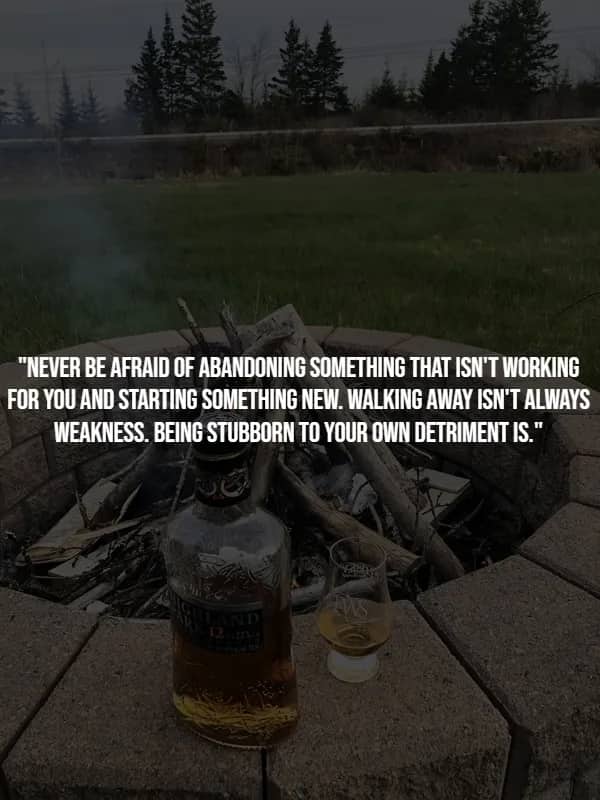 Highland whisky bottle and glass perched on a fire pit at dusk, illustrating the wisdom of a well-timed strategic retreat.