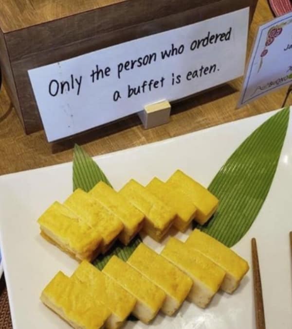 threatening translation fail at a food station. A sign meant to restrict the food to paying customers instead suggests a grim fate for the diners: "Only the person who ordered a buffet is eaten."