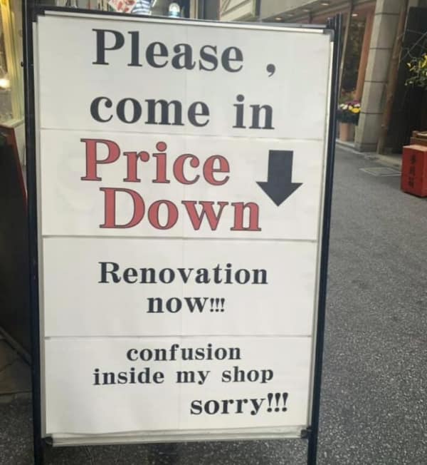 chaotic translation fail on a sandwich board outside a Japanese shop. It attempts to explain ongoing construction but ends up sounding like a warning about the store's internal state. The text reads: "Please, come in / Price Down / Renovation now!!! / confusion inside my shop sorry!!!"