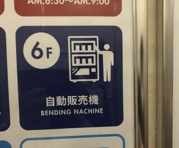 literal translation fail on a directional sign. A blue square features a pictogram of a person reaching into a vending machine, but the English text below the Japanese characters identifies it as a "BENDING NACHINE," likely a typo for "vending machine."