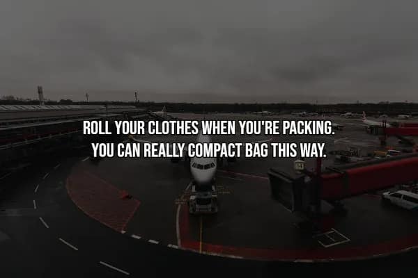 High-Octane Alt Text (Part 1, Images 1-10) Image 1 A travel hack tip presented over a dark, moody shot of an airplane at an airport gate. The white text reads: ROLL YOUR CLOTHES WHEN YOU'RE PACKING. YOU CAN REALLY COMPACT BAG THIS WAY. This technique is a staple for travelers looking to maximize luggage space and minimize wrinkles.
