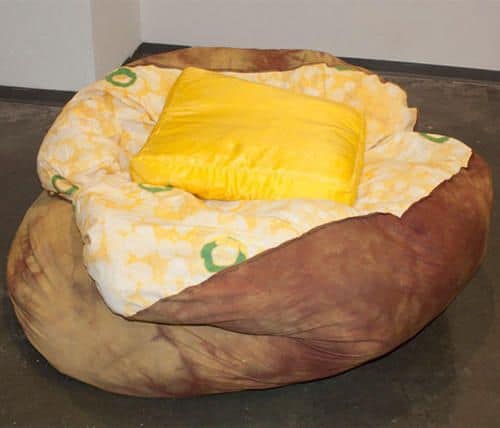 Giant baked potato bean bag chair with butter yellow pillow in gallery space
