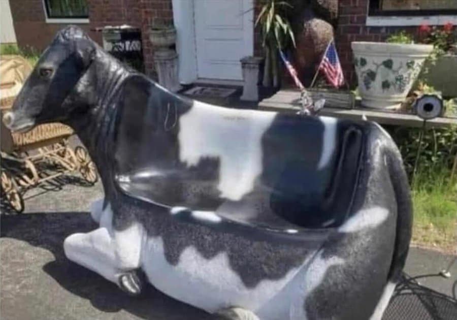 Black and white dairy cow shaped plastic outdoor chair sitting in residential driveway