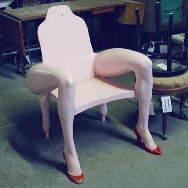 Unusual pink chair with realistic human leg armrests and red high heel shoe feet in thrift store
