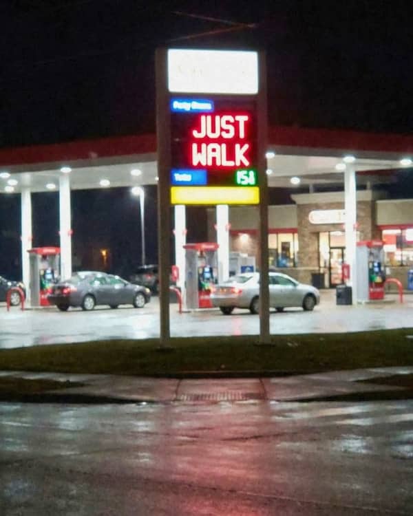 Unpopular opinion meme of illuminated gas station sign at night reading "JUST WALK" above prices