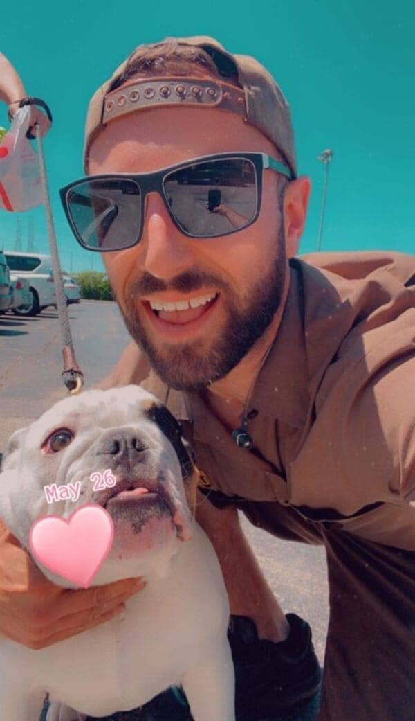 UPS driver takes selfie with white bulldog wearing pink heart filter with May 26 date