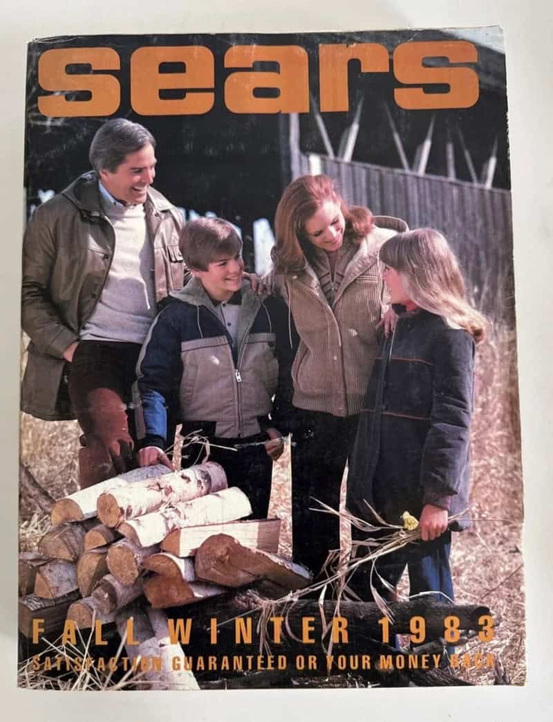 Worn 1983 Fall Winter Sears catalog cover featuring family in winter coats by woodpile in autumn field