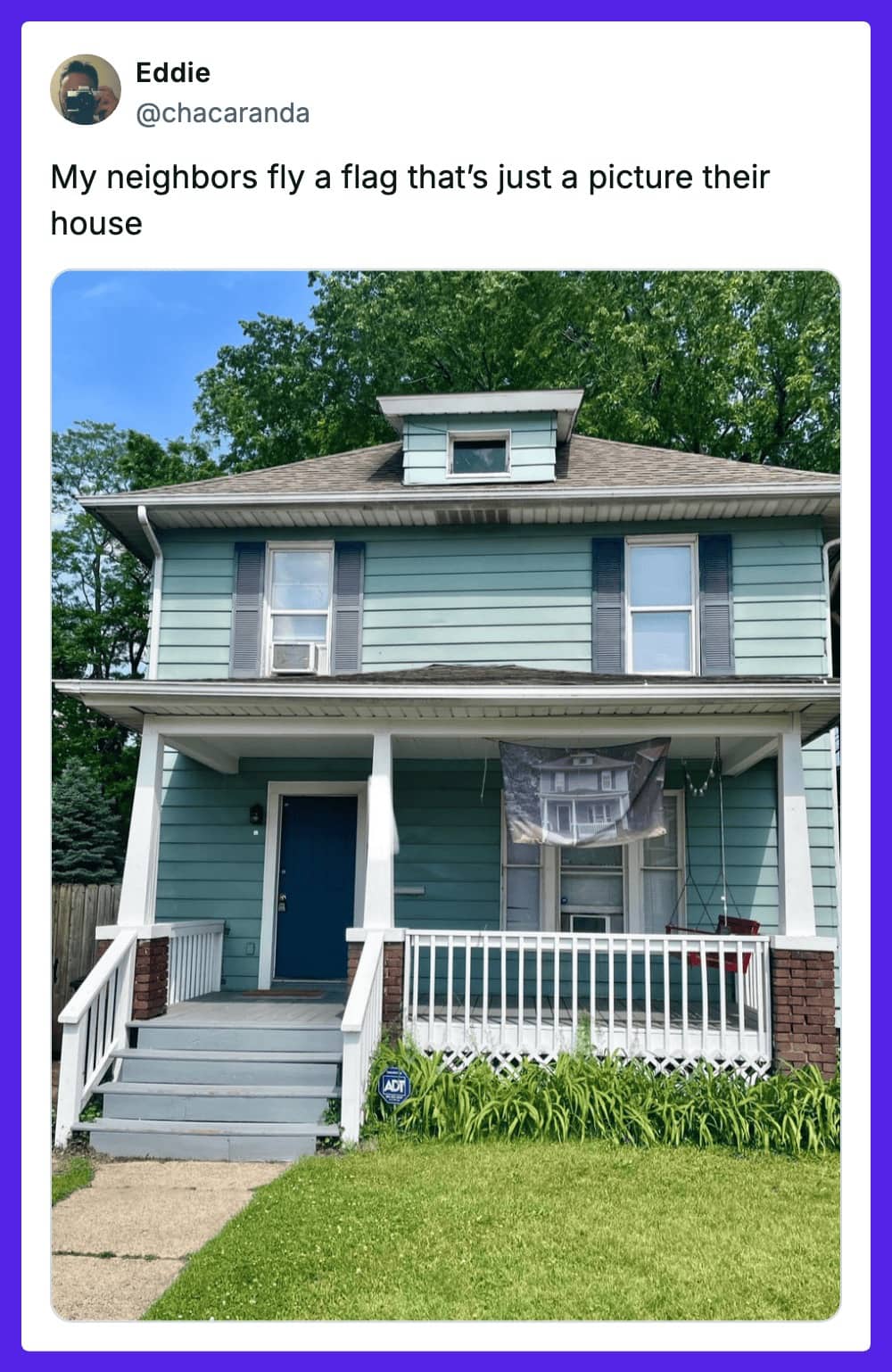 A photo of a house flying a custom flag that is just a picture of the house.