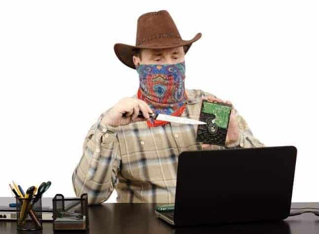 Weird stock photo of cowboy bandit threatening computer hard drive with large kitchen knife