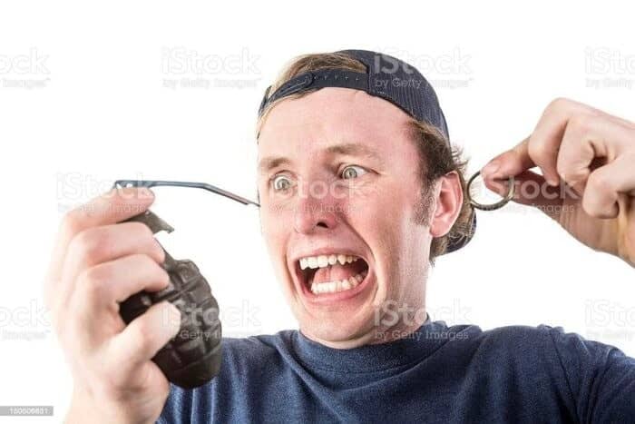 Weird stock photo of terrified man biting grenade pin while person pulls the handle