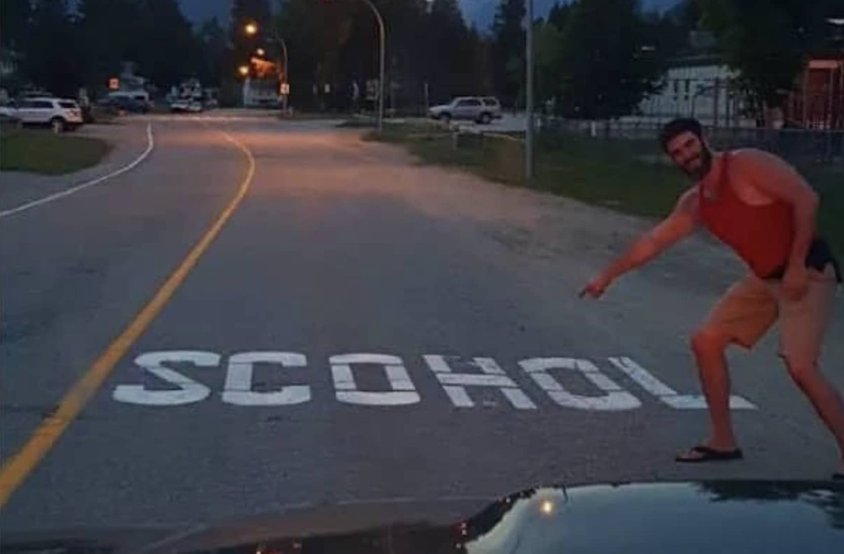 Funny typo meme showing a man pointing at a street sign misspelled as SCOHOOL.