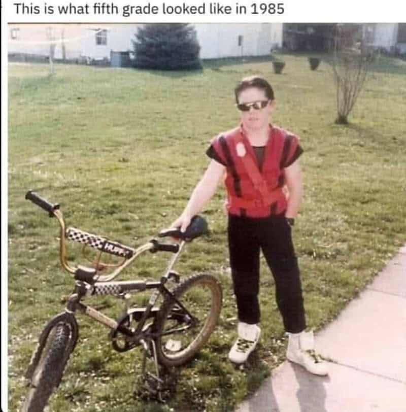 A classic Gen X meme featuring a 1985 fifth-grader striking a pose with a Huffy BMX bike, wearing aviator sunglasses, a red padded vest, black pants, and crisp white high-top sneakers.