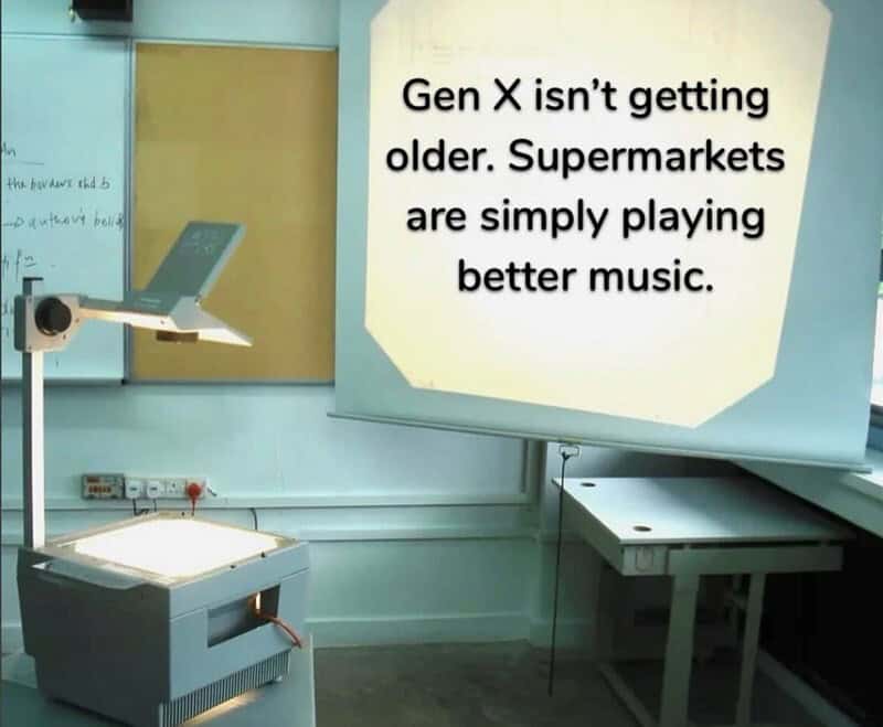 relatable Gen X meme showing an old-school overhead projector in a classroom, with the projected text stating that Gen X isn't aging—supermarkets are just finally playing better music.