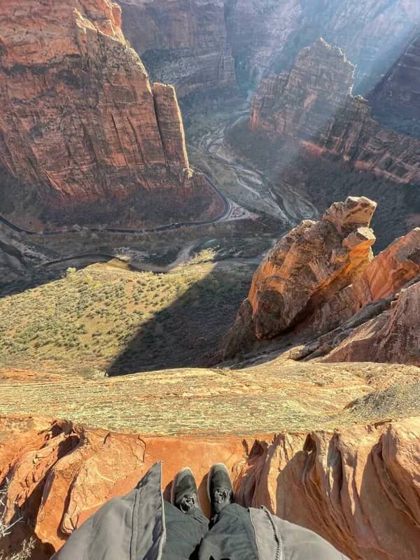 First-person view of boots standing on a high Zion canyon rim.