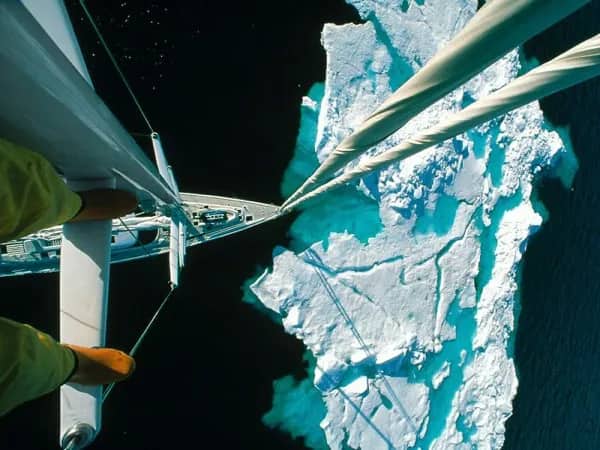 First-person view from a boat mast, showing a person's boots looking down at icebergs.
