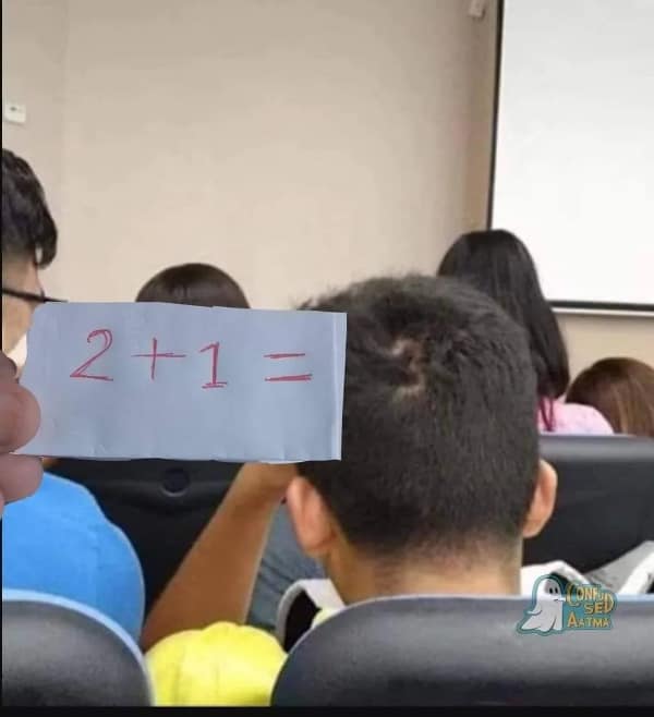A classroom prank setup forms a viral blursed image when a hand positions a paper slip with the math equation "2 + 1 =" directly behind a student’s head whose natural hair whorl forms a perfect digit 3.
