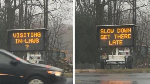 A two-panel roadside electronic construction sign displays a humorous traffic advisory warning drivers visiting their in-laws to slow down and arrive late, captured as a blursed image.