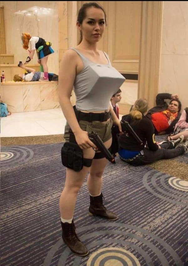 A dedicated convention cosplayer outfits herself as video game protagonist Lara Croft from the 1996 Tomb Raider franchise, incorporating a custom low-polygon angular chest prosthetic to mimic vintage PlayStation graphics in a viral blursed image.