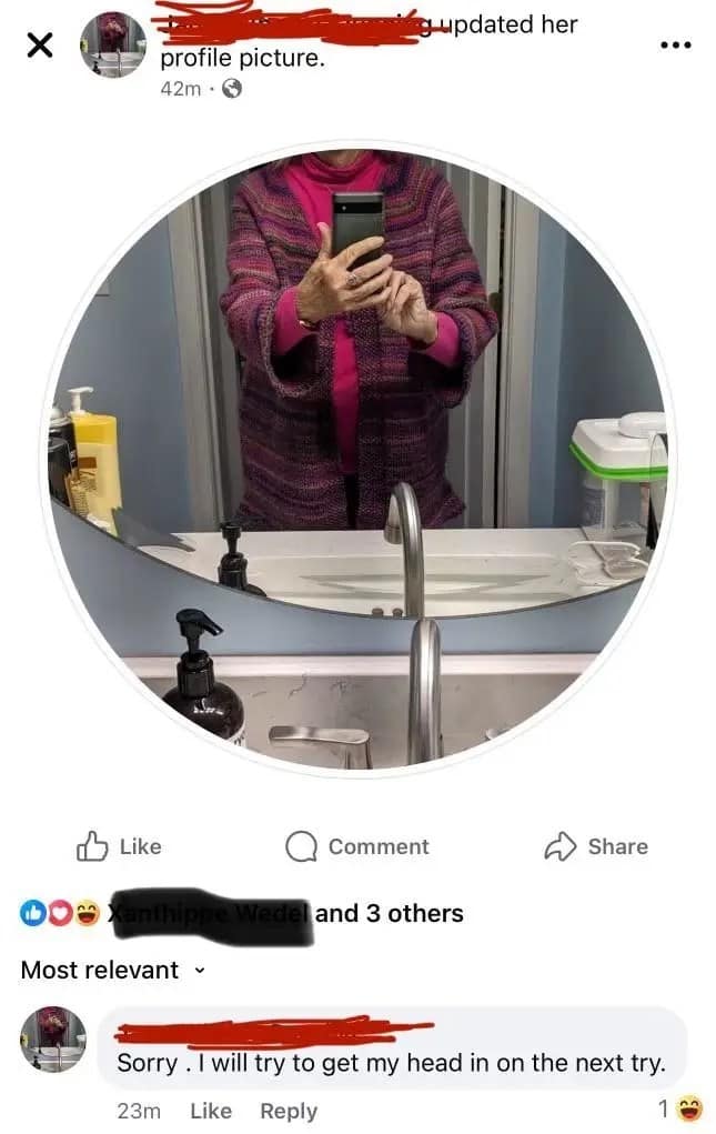 Facebook profile picture update showing a vertical mirror selfie that has been cropped into a circle. The photo only captures the person from the neck down, showcasing a vibrant pink turtleneck under a purple and magenta knit cardigan. Below the post, the user has commented on their own photo, "Sorry . I will try to get my head in on the next try."