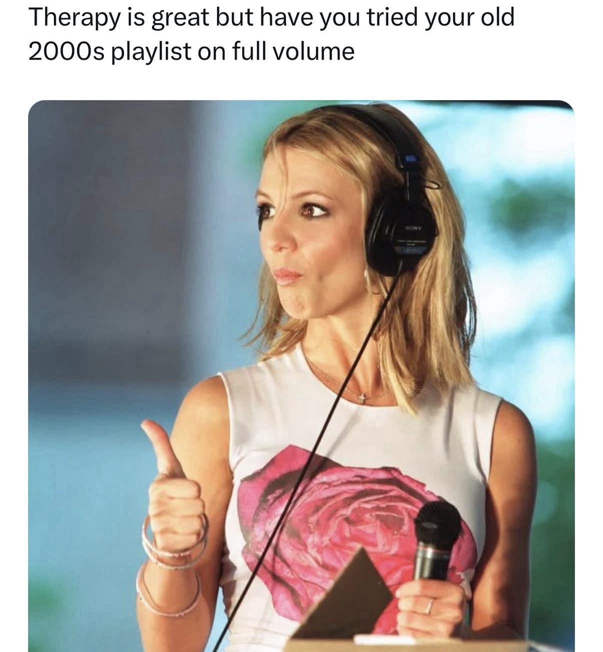 Pop superstar Britney Spears wearing large black studio headphones and giving a thumbs up anchors a classic meme championing the therapeutic healing power of a loud 2000s music playlist.