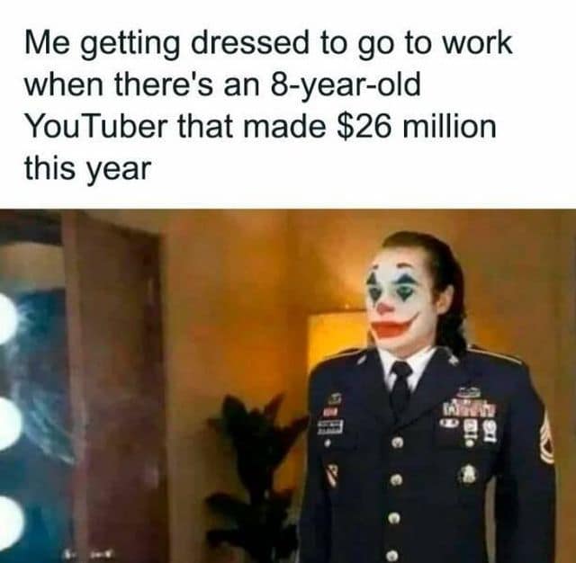 A classic meme featuring Joaquin Phoenix’s Joker photoshopped into a high-ranking military dress uniform. The text describes the internal defeat of getting dressed for a regular job while realizing an 8-year-old YouTuber earned $26 million in a single year.