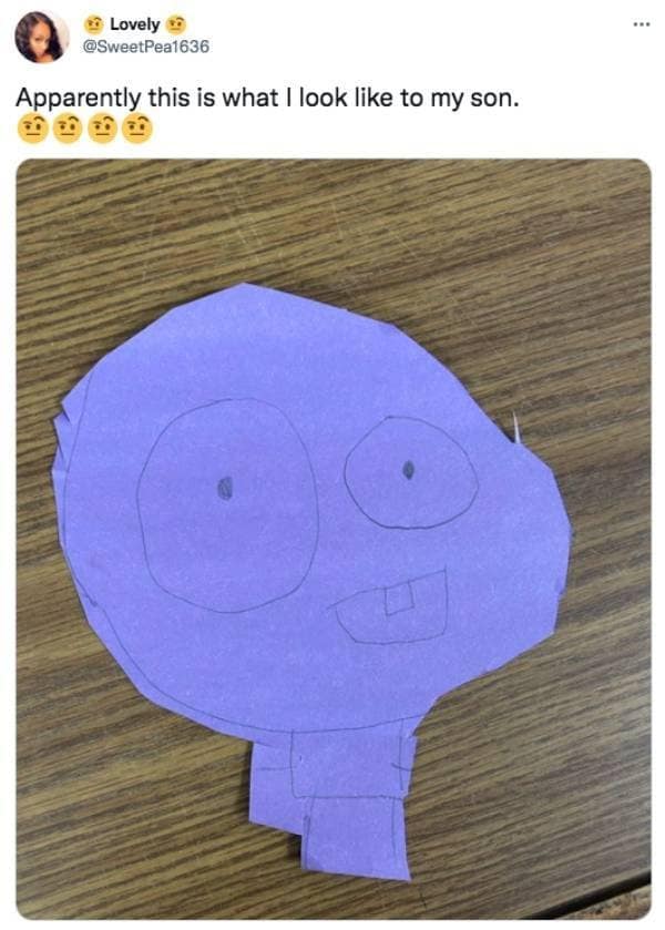 A lighthearted family craft project shared as a funny classic meme highlights an X platform update by user Lovely, showcasing a bizarre purple construction paper cutout head with unevenly drawn eyes and a single square block tooth drawn by her son.