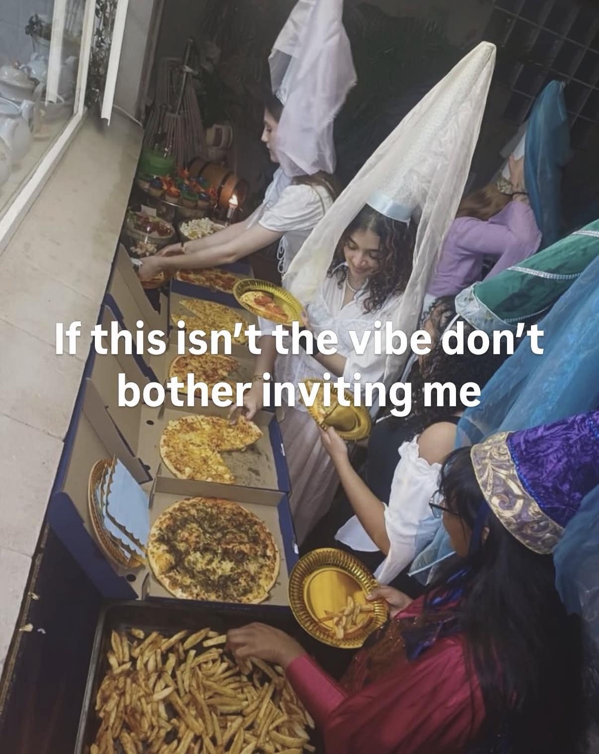 Young women dressed in medieval hennin cone hats and veils grab slices of pizza from delivery boxes in a viral classic meme about defining the perfect party vibe.