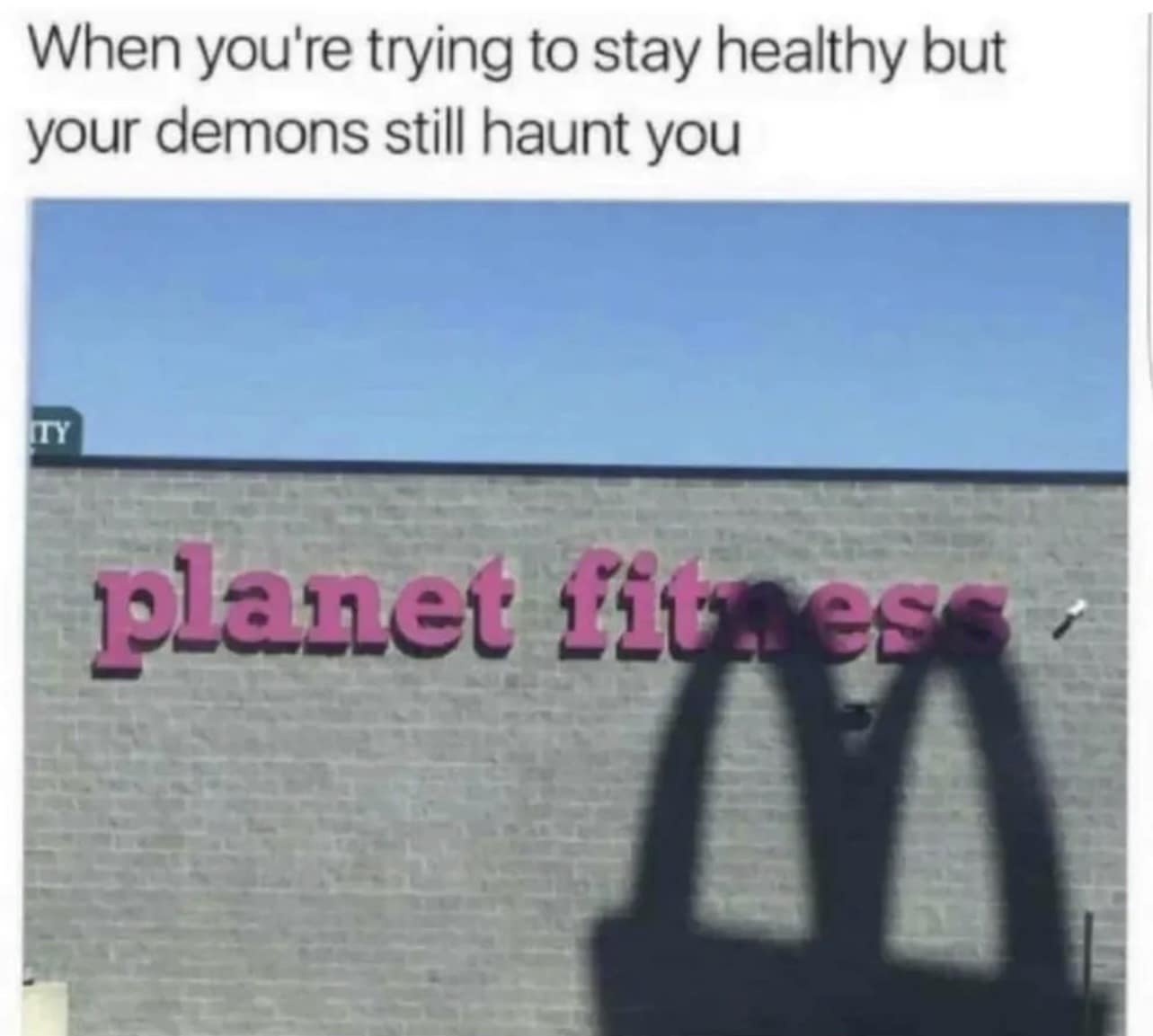 classic meme about dietary discipline, showing a Planet Fitness gym exterior cast with the massive, ominous shadow of the McDonald's golden arches under the caption, "When you're trying to stay healthy but your demons still haunt you."
