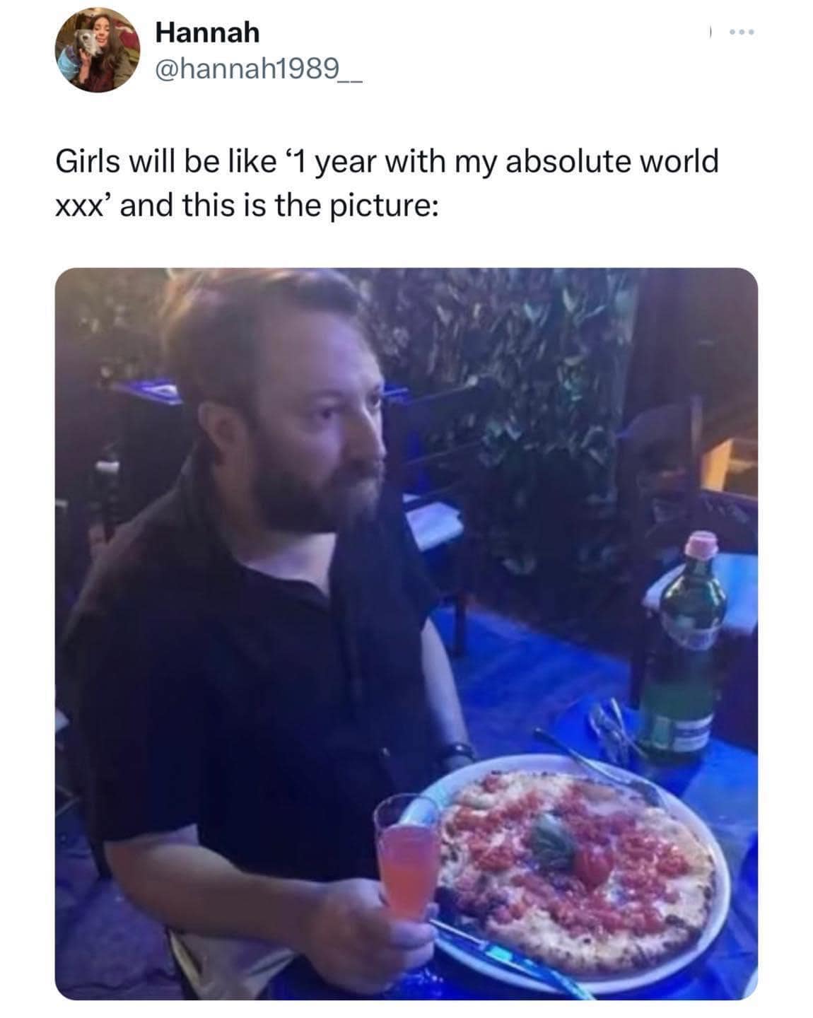 A Twitter post captures a viral classic meme contrasting a girl's hyper-romantic anniversary caption against a hilariously dim, unenthusiastic photo of a man sitting in a restaurant with a pizza.