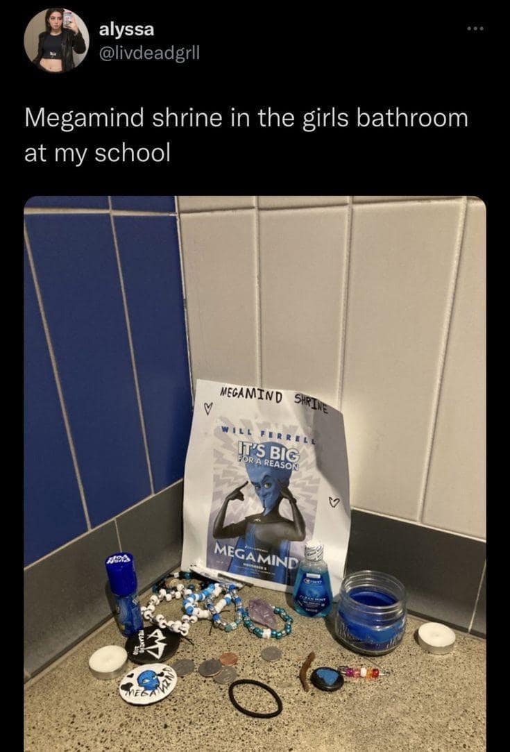 A bizarrely dedicated "Megamind Shrine" tucked into the corner of a school bathroom, complete with a Will Ferrell poster, blue candles, coins, and beads.