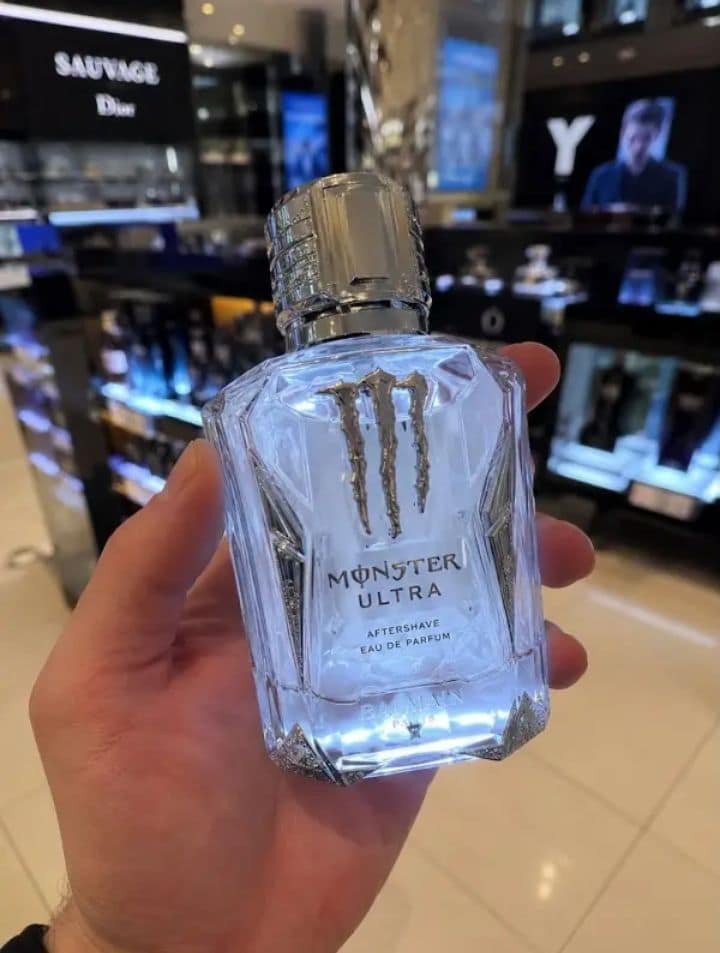 A luxury retail mashup operates as a funny classic meme, showing a hand holding a high-end crystal cologne flacon photoshopped with the Monster Energy three-claw scratch graphic to read "MONSTER ULTRA AFTERSHAVE EAU DE PARFUM."