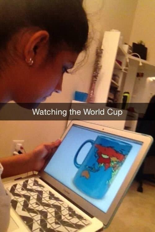 A visual pun classic meme showing a person holding a laptop displaying a photo of a mug with a world map on it, with a Snapchat bar reading "Watching the World Cup."