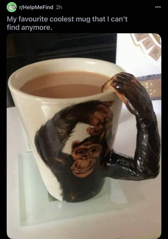 A white ceramic mug with a realistic chimpanzee painting and a 3D monkey arm handle.