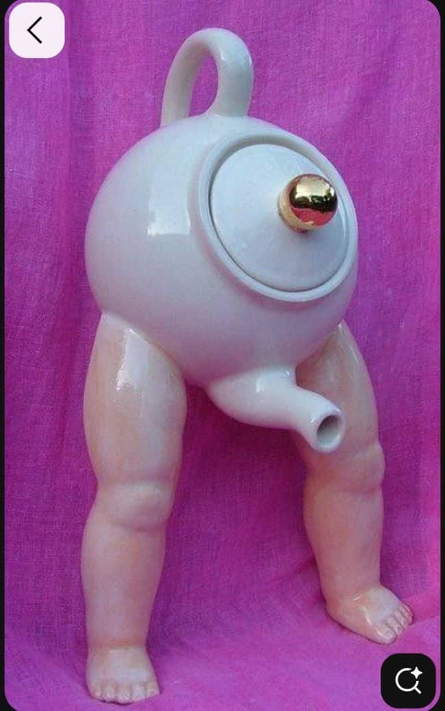 A bizarre white teapot with realistic baby legs and a spout positioned between the thighs.