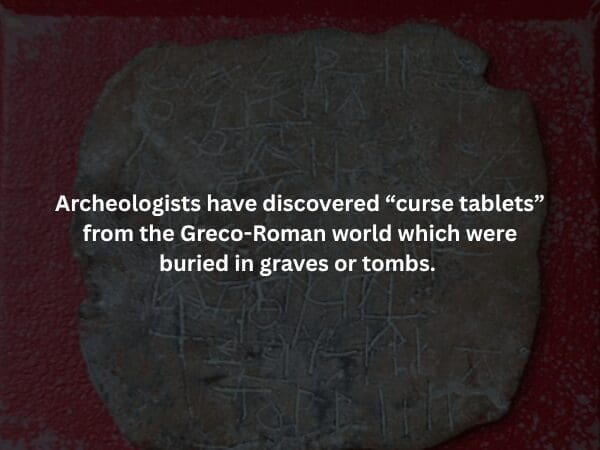 A dark, textured image of an ancient lead Greco-Roman "curse tablet" covered in jagged, etched inscriptions, with text explaining they were often buried in graves to invoke spirits against enemies.