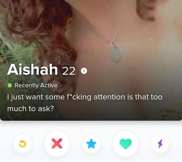 A close-up screenshot of a funny dating app profile for 22-year-old Aishah displays a heart pendant necklace below an aggressively honest bio line stating, "I just want some f*cking attention is that too much to ask?"