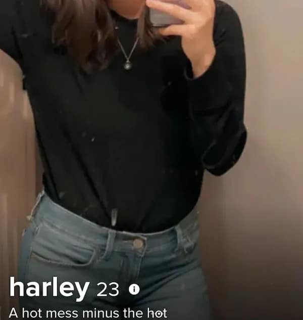 A basic mirror torso selfie forms a cringy tinder profile card for 23-year-old Harley in a black long-sleeve shirt and denim jeans, utilizing a deeply self-deprecating subverted phrase reading, "A hot mess minus the hot."