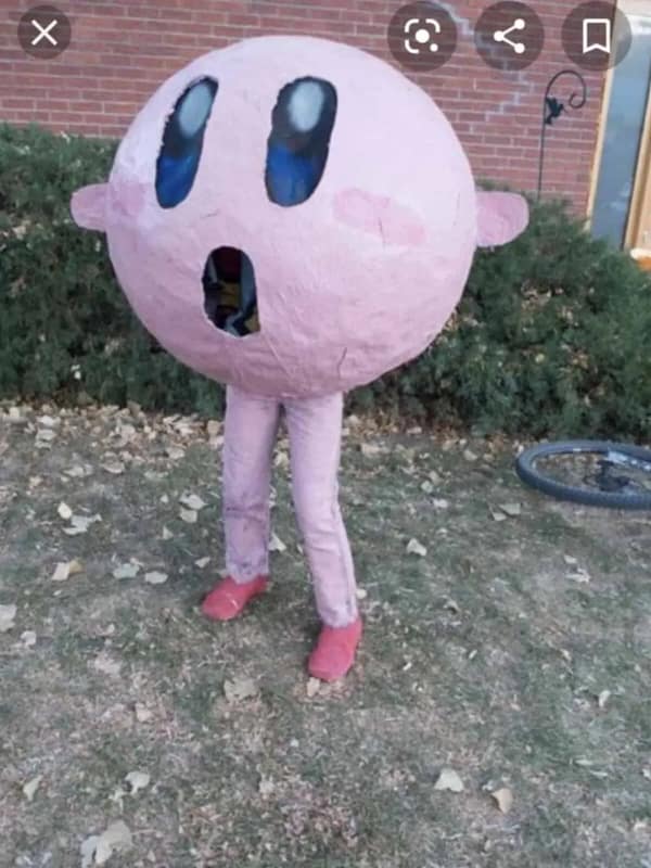 A haunting cursed cosplay of Kirby consisting of a massive pink paper-mache sphere for a head on top of regular human legs, with a dark mouth hole revealing the person inside.