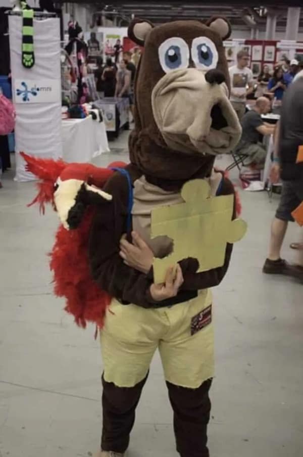 A sagging, poorly constructed cursed cosplay of Banjo-Kazooie at a convention, featuring a limp bear head and a bird puppet that looks like it’s screaming for help.