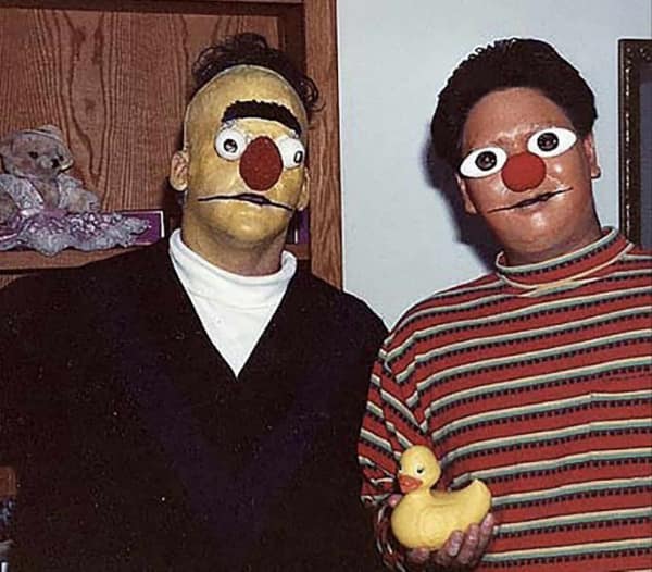terrifyingly realistic and cursed cosplay of Bert and Ernie featuring distorted masks with uncomfortably human eyes and oily textures.