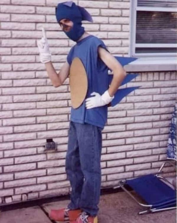 A vintage-looking cursed cosplay of Sonic the Hedgehog featuring a lanky man in a blue sleeveless shirt with cardboard spikes and a blue balaclava.