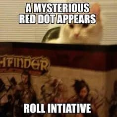 A domestic white cat glaring over the edge of a tabletop Pathfinder storyteller shield stars in a funny dnd meme about a laser pointer red dot trigger.