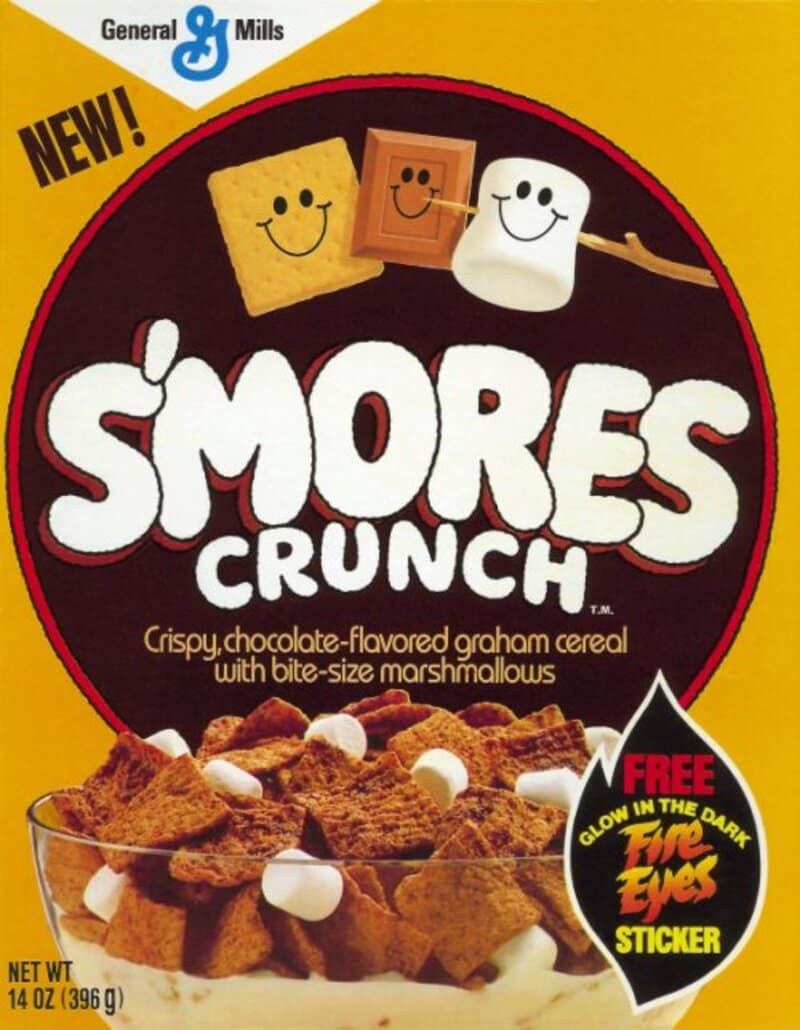 A classic box of General Mills S'mores Crunch cereal brings back memories of popular discontinued cereals, showing cartoon marshmallow, graham cracker, and chocolate bar characters smiling together.