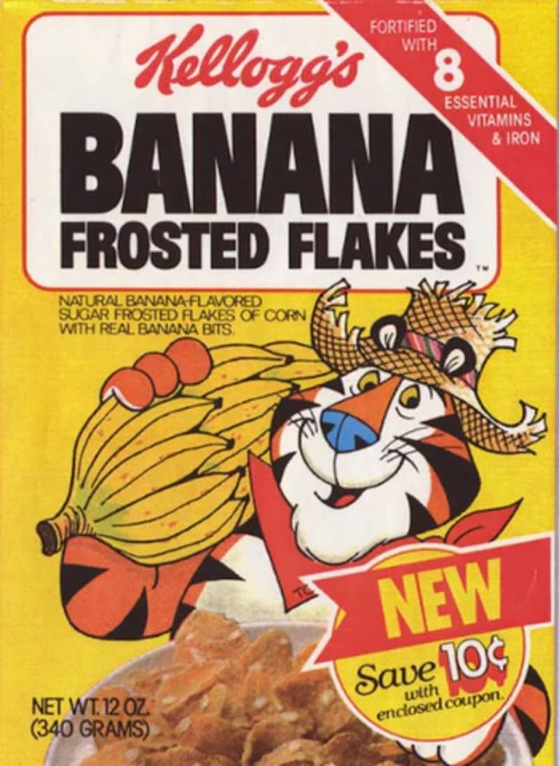 A vintage box of Kellogg's Banana Frosted Flakes captures a rare flavor variant in the history of discontinued cereals, showing Tony the Tiger sporting a straw hat while carrying a large bunch of bananas.
