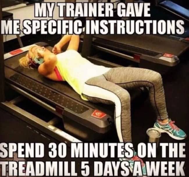 An gym humor photo showing a woman lying flat on her back on top of a stationary treadmill.